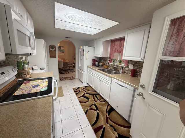 17569 SE 107th Ct, Summerfield, FL 34491 - kitchen featuring white appliances, arched walkways, decorative backsplash, light tile patterned floors, and a textured ceiling