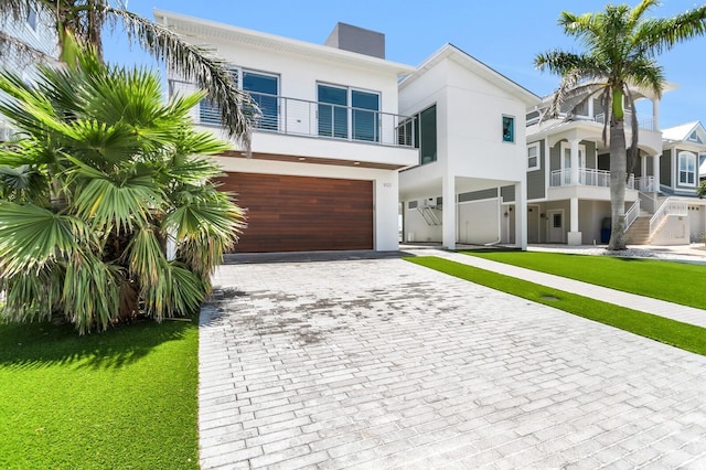 905 Bay Point Dr, Madeira Beach, FL 33708 - view of front facade with stucco siding, decorative driveway, an attached garage, a front yard, and a chimney