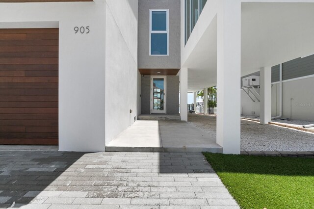 905 Bay Point Dr, Madeira Beach, FL 33708 - view of exterior entry with stucco siding and a wall unit AC