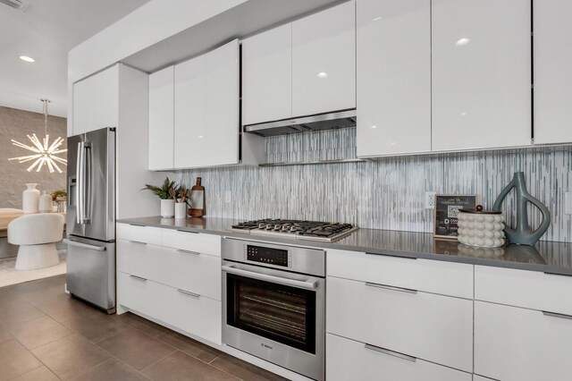 905 Bay Point Dr, Madeira Beach, FL 33708 - kitchen with stainless steel appliances, modern cabinets, white cabinetry, a chandelier, and dark tile patterned flooring