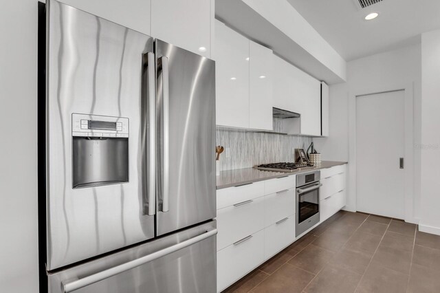 905 Bay Point Dr, Madeira Beach, FL 33708 - kitchen featuring stainless steel appliances, modern cabinets, white cabinets, tasteful backsplash, and light countertops