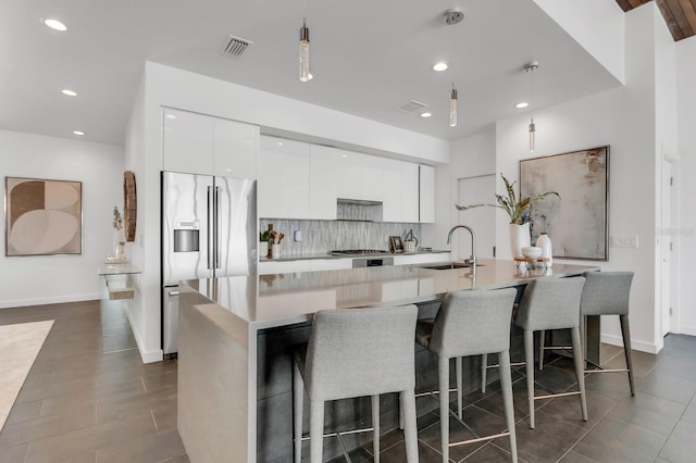 905 Bay Point Dr, Madeira Beach, FL 33708 - kitchen with stainless steel fridge with ice dispenser, modern cabinets, white cabinets, decorative backsplash, and recessed lighting
