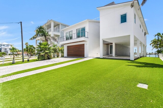 905 Bay Point Dr, Madeira Beach, FL 33708 - contemporary house with driveway, a front yard, stucco siding, and an attached garage