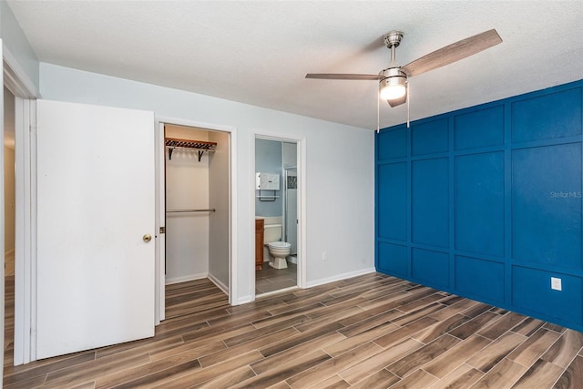 89 Fremont Ave Unit 504, Daytona Beach, FL 32114 - unfurnished bedroom featuring wood finished floors, a decorative wall, connected bathroom, ceiling fan, and a textured ceiling