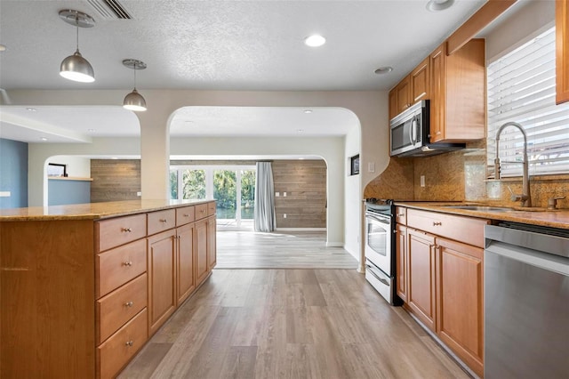 6814 68th Ave E, Bradenton, FL 34203 - kitchen with appliances with stainless steel finishes, light wood-style flooring, light stone countertops, decorative backsplash, and decorative light fixtures