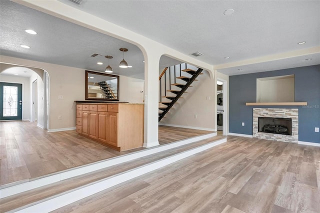 6814 68th Ave E, Bradenton, FL 34203 - unfurnished living room with arched walkways, light wood-style floors, stairs, a stone fireplace, and recessed lighting