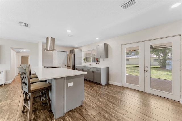 9819 Allen Rd, Lithia, FL 33547 - kitchen with gray cabinetry, freestanding refrigerator, french doors, island exhaust hood, and a kitchen breakfast bar