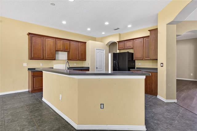 1835 Fircrest Ct, Wesley Chapel, FL 33543 - kitchen with black refrigerator with ice dispenser, arched walkways, a large island, dark countertops, and recessed lighting