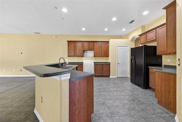 1835 Fircrest Ct, Wesley Chapel, FL 33543 - kitchen with black fridge with ice dispenser, dark countertops, an island with sink, tile patterned floors, and a textured ceiling