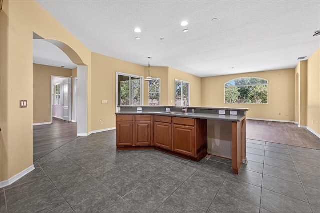 1835 Fircrest Ct, Wesley Chapel, FL 33543 - kitchen with a textured ceiling, dark countertops, recessed lighting, a kitchen island with sink, and arched walkways