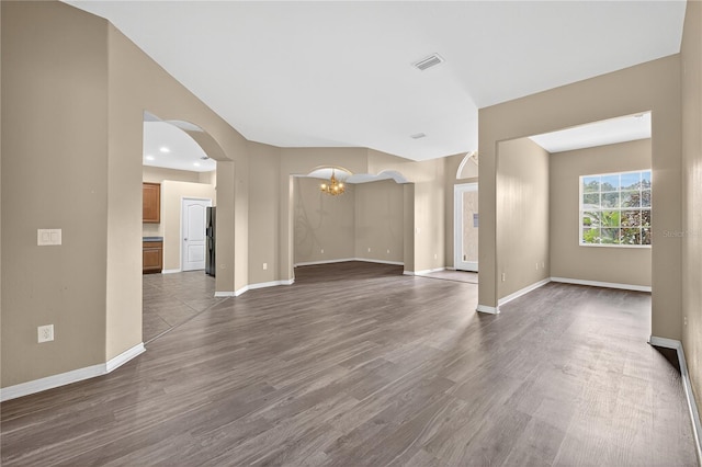 1835 Fircrest Ct, Wesley Chapel, FL 33543 - unfurnished living room featuring arched walkways, a chandelier, and dark wood-type flooring