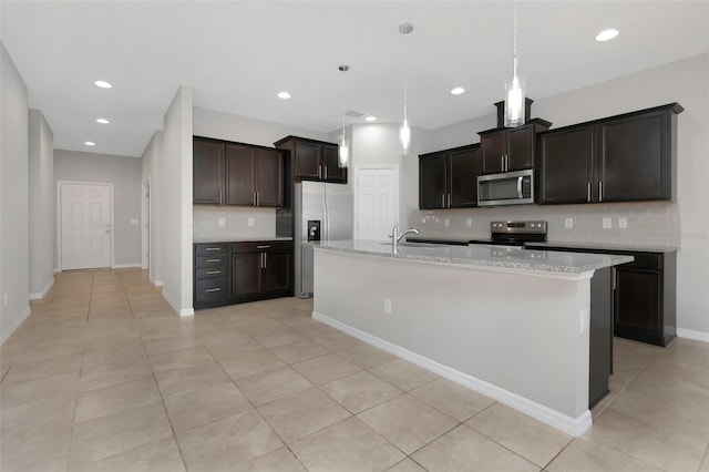 1613 Cabbage Key Dr, Ruskin, FL 33570 - kitchen with appliances with stainless steel finishes, tasteful backsplash, light tile patterned floors, a kitchen island with sink, and pendant lighting