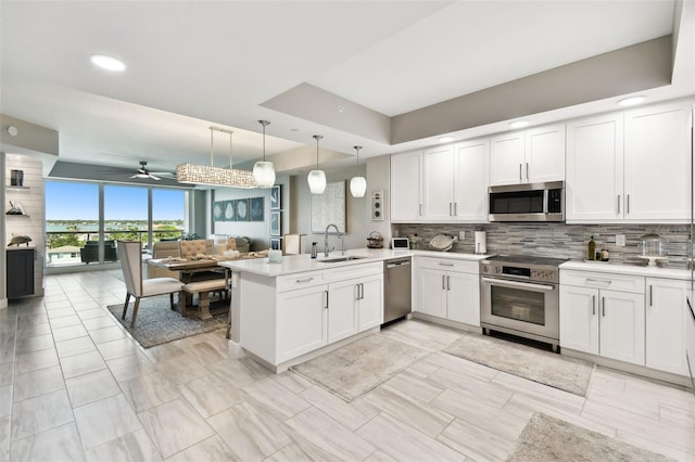 415 Island Way Unit 507, Clearwater Beach, FL 33767 - kitchen featuring stainless steel appliances, a peninsula, open floor plan, decorative backsplash, and white cabinets