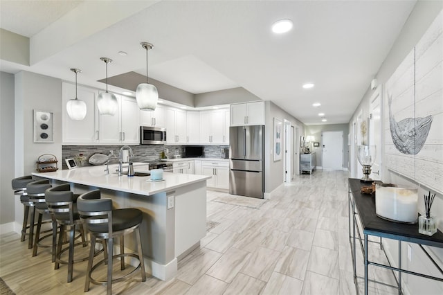 415 Island Way Unit 507, Clearwater Beach, FL 33767 - kitchen with appliances with stainless steel finishes, a peninsula, a breakfast bar area, white cabinets, and backsplash