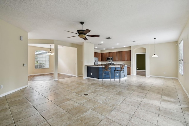 297 Beacon Pointe Dr, Ocoee, FL 34761 - unfurnished living room featuring light tile patterned flooring, a ceiling fan, recessed lighting, a textured ceiling, and arched walkways