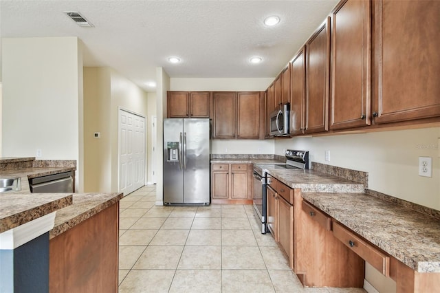 297 Beacon Pointe Dr, Ocoee, FL 34761 - kitchen with appliances with stainless steel finishes, light tile patterned flooring, recessed lighting, a textured ceiling, and brown cabinets