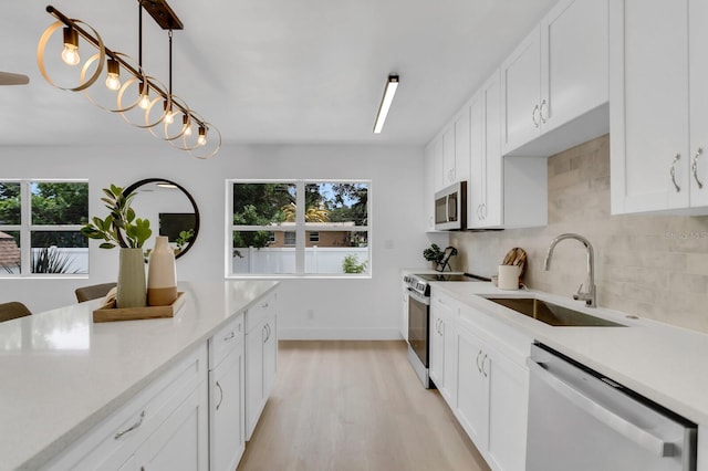 3381 19th Pl SW, Largo, FL 33774 - kitchen with stainless steel appliances, light countertops, decorative backsplash, light wood-style floors, and white cabinetry