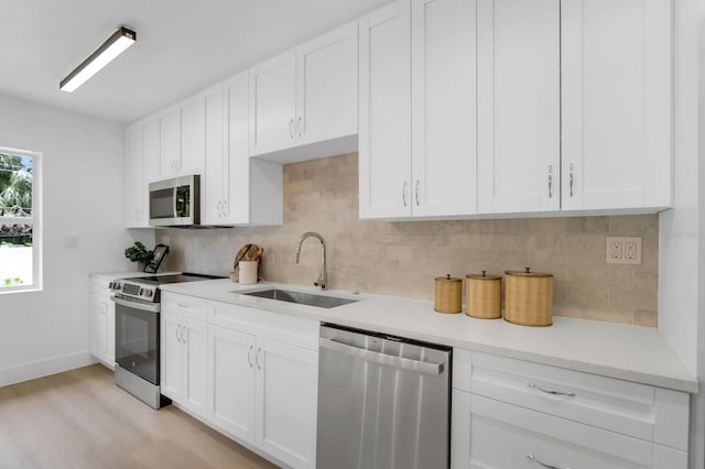 3381 19th Pl SW, Largo, FL 33774 - kitchen featuring appliances with stainless steel finishes, light wood finished floors, white cabinets, and tasteful backsplash