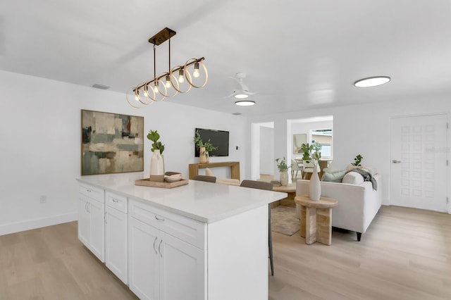 3381 19th Pl SW, Largo, FL 33774 - kitchen featuring light wood-type flooring, white cabinetry, light countertops, a breakfast bar, and a ceiling fan