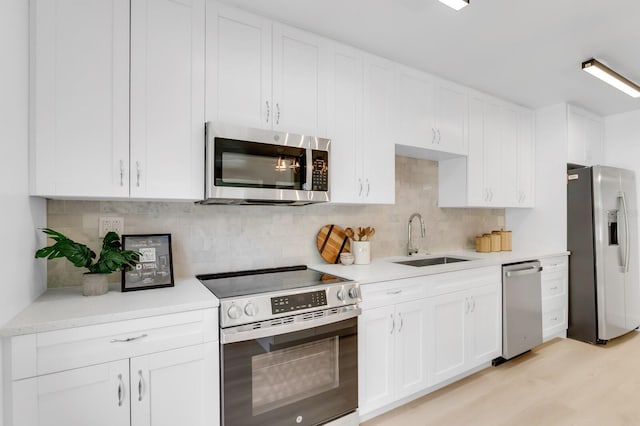 3381 19th Pl SW, Largo, FL 33774 - kitchen with appliances with stainless steel finishes, white cabinetry, decorative backsplash, light countertops, and light wood-type flooring