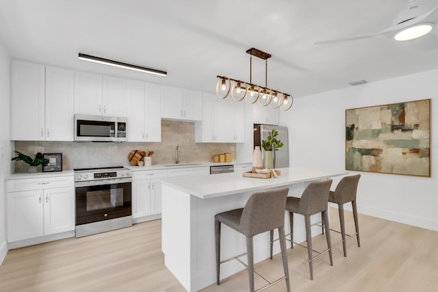 3381 19th Pl SW, Largo, FL 33774 - kitchen featuring stainless steel appliances, light wood-style floors, tasteful backsplash, and a kitchen breakfast bar
