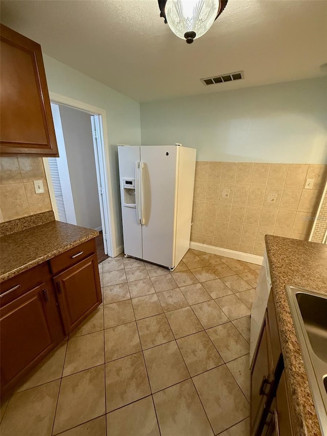 1020 85th Ave N Unit 223, Saint Petersburg, FL 33702 - kitchen featuring white refrigerator with ice dispenser, light tile patterned floors, dark countertops, and backsplash