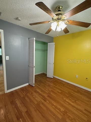1020 85th Ave N Unit 223, Saint Petersburg, FL 33702 - unfurnished bedroom featuring wood finished floors, a textured ceiling, a closet, and ceiling fan