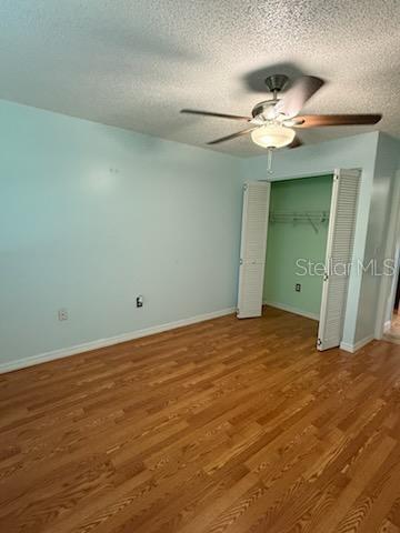 1020 85th Ave N Unit 223, Saint Petersburg, FL 33702 - unfurnished bedroom featuring wood finished floors, a textured ceiling, ceiling fan, and a closet