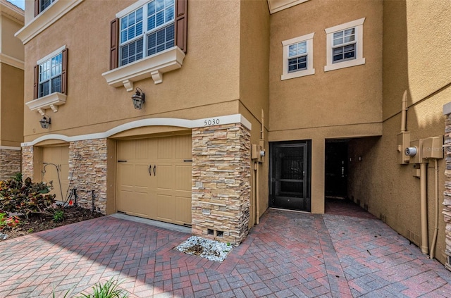 5030 Herring Ct, New Port Richey, FL 34652 - view of exterior entry with stone siding, stucco siding, and an attached garage