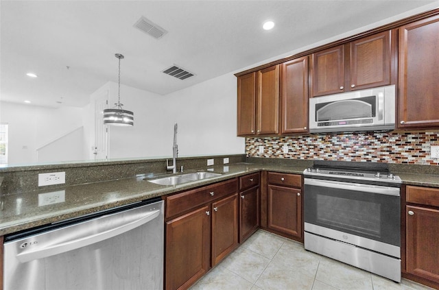 5030 Herring Ct, New Port Richey, FL 34652 - kitchen with appliances with stainless steel finishes, light tile patterned floors, dark stone countertops, backsplash, and hanging light fixtures
