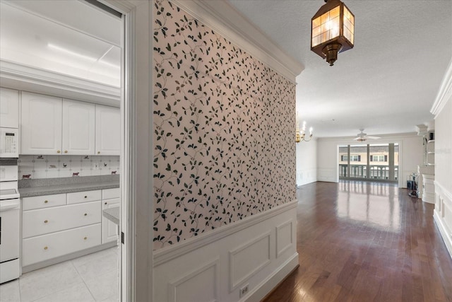139 Bluff View Dr Unit 405, Belleair Bluffs, FL 33770 - corridor featuring a wainscoted wall, ornamental molding, a textured ceiling, light wood-type flooring, and a chandelier