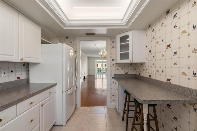 139 Bluff View Dr Unit 405, Belleair Bluffs, FL 33770 - kitchen featuring freestanding refrigerator, white cabinets, dark countertops, a chandelier, and ornamental molding
