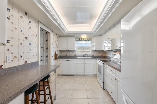 139 Bluff View Dr Unit 405, Belleair Bluffs, FL 33770 - kitchen featuring white appliances, dark countertops, light tile patterned floors, a raised ceiling, and white cabinets