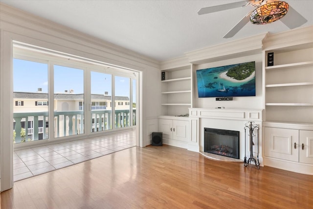 139 Bluff View Dr Unit 405, Belleair Bluffs, FL 33770 - unfurnished living room with wood finished floors, ceiling fan, built in features, a glass covered fireplace, and crown molding