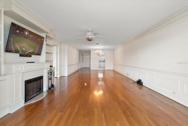 139 Bluff View Dr Unit 405, Belleair Bluffs, FL 33770 - unfurnished living room with a chandelier, a ceiling fan, a fireplace, wood finished floors, and crown molding