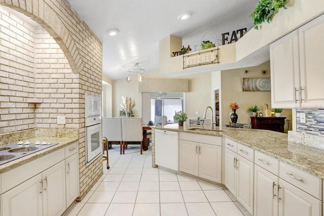 7101 Bucks Ford Dr, Riverview, FL 33578 - kitchen featuring white appliances, tasteful backsplash, a peninsula, light tile patterned floors, and white cabinets
