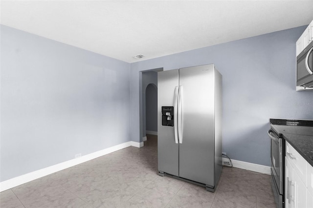 9310 N 12th St, Tampa, FL 33612 - kitchen featuring appliances with stainless steel finishes, white cabinets, arched walkways, and dark stone counters