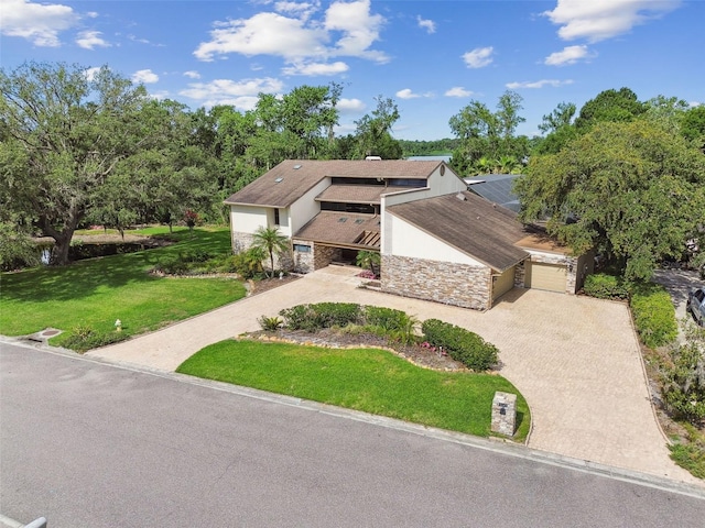 2103 N Golfview Dr, Plant City, FL 33566 - mid-century modern home with decorative driveway, a front lawn, an attached garage, and stone siding