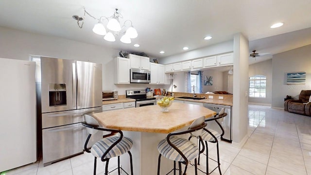 7010 Kendall Heath Way, Land O Lakes, FL 34637 - kitchen featuring appliances with stainless steel finishes, light countertops, a breakfast bar, light tile patterned floors, and recessed lighting