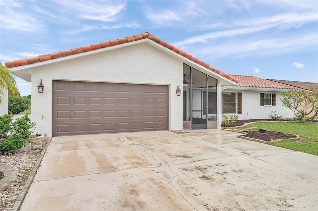 734 Flamingo Dr, Apollo Beach, FL 33572 - view of front of home with a tile roof, brick siding, concrete driveway, an attached garage, and a sunroom