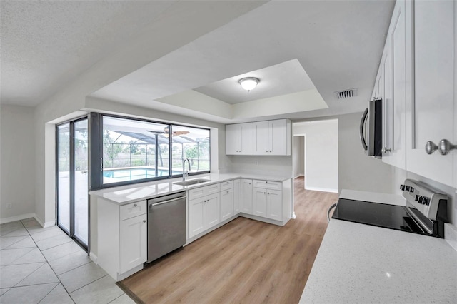 734 Flamingo Dr, Apollo Beach, FL 33572 - kitchen featuring appliances with stainless steel finishes, a tray ceiling, light countertops, and white cabinets