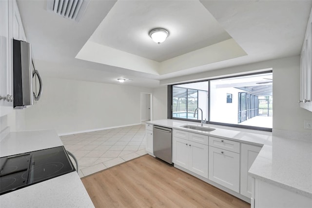 734 Flamingo Dr, Apollo Beach, FL 33572 - kitchen with appliances with stainless steel finishes, a raised ceiling, white cabinetry, and plenty of natural light