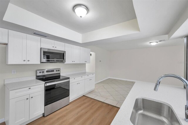 734 Flamingo Dr, Apollo Beach, FL 33572 - kitchen with appliances with stainless steel finishes, light countertops, white cabinets, and light wood-style flooring