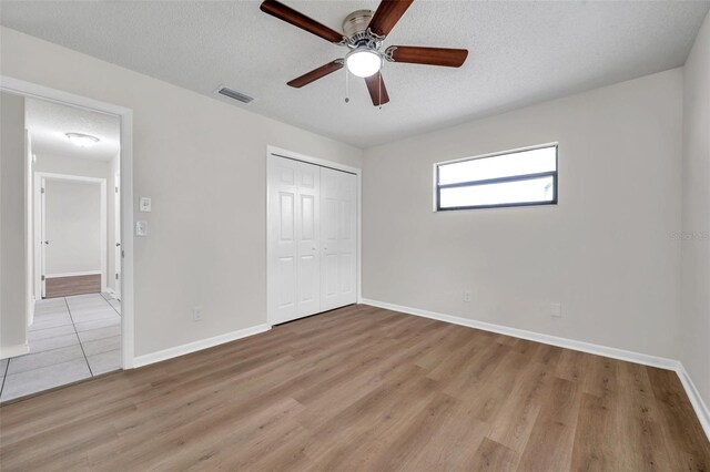 734 Flamingo Dr, Apollo Beach, FL 33572 - unfurnished bedroom featuring light wood-style flooring, a closet, a textured ceiling, and ceiling fan