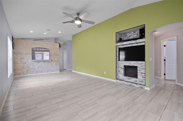 8526 Quarter Horse Dr, Riverview, FL 33578 - unfurnished living room with lofted ceiling, a ceiling fan, a stone fireplace, arched walkways, and light wood-style floors