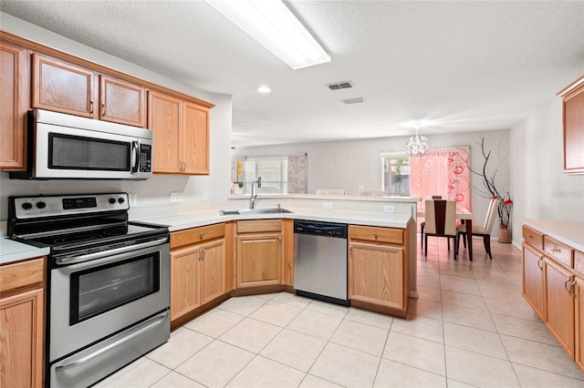 17509 Queensland St, Land O Lakes, FL 34638 - kitchen featuring appliances with stainless steel finishes, a peninsula, light countertops, light tile patterned flooring, and recessed lighting