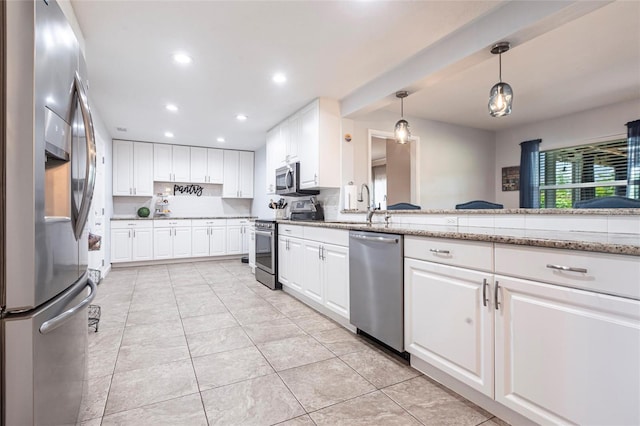 3312 Kenmore Dr, Sarasota, FL 34231 - kitchen featuring appliances with stainless steel finishes, recessed lighting, white cabinetry, pendant lighting, and light stone counters