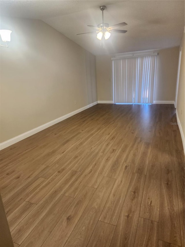209 Corkwood Ln, Oldsmar, FL 34677 - empty room featuring wood finished floors, a ceiling fan, and vaulted ceiling