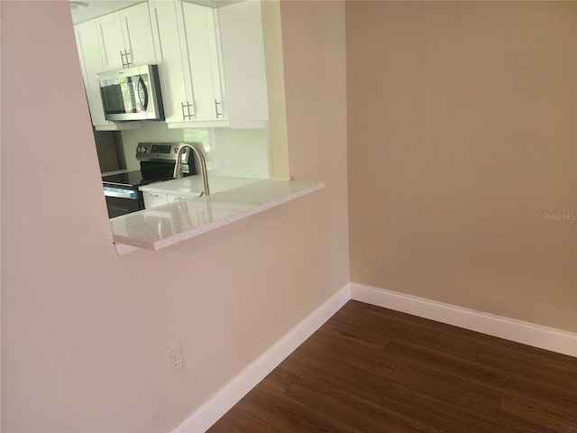 209 Corkwood Ln, Oldsmar, FL 34677 - kitchen featuring stainless steel appliances, dark wood-style floors, white cabinets, light stone counters, and a kitchen breakfast bar
