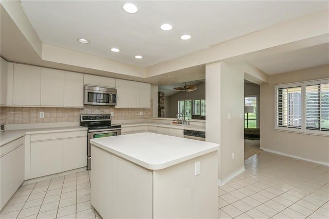 3262 Westcott Ct, Palm Harbor, FL 34684 - kitchen featuring stainless steel appliances, light tile patterned floors, tasteful backsplash, a center island, and light countertops